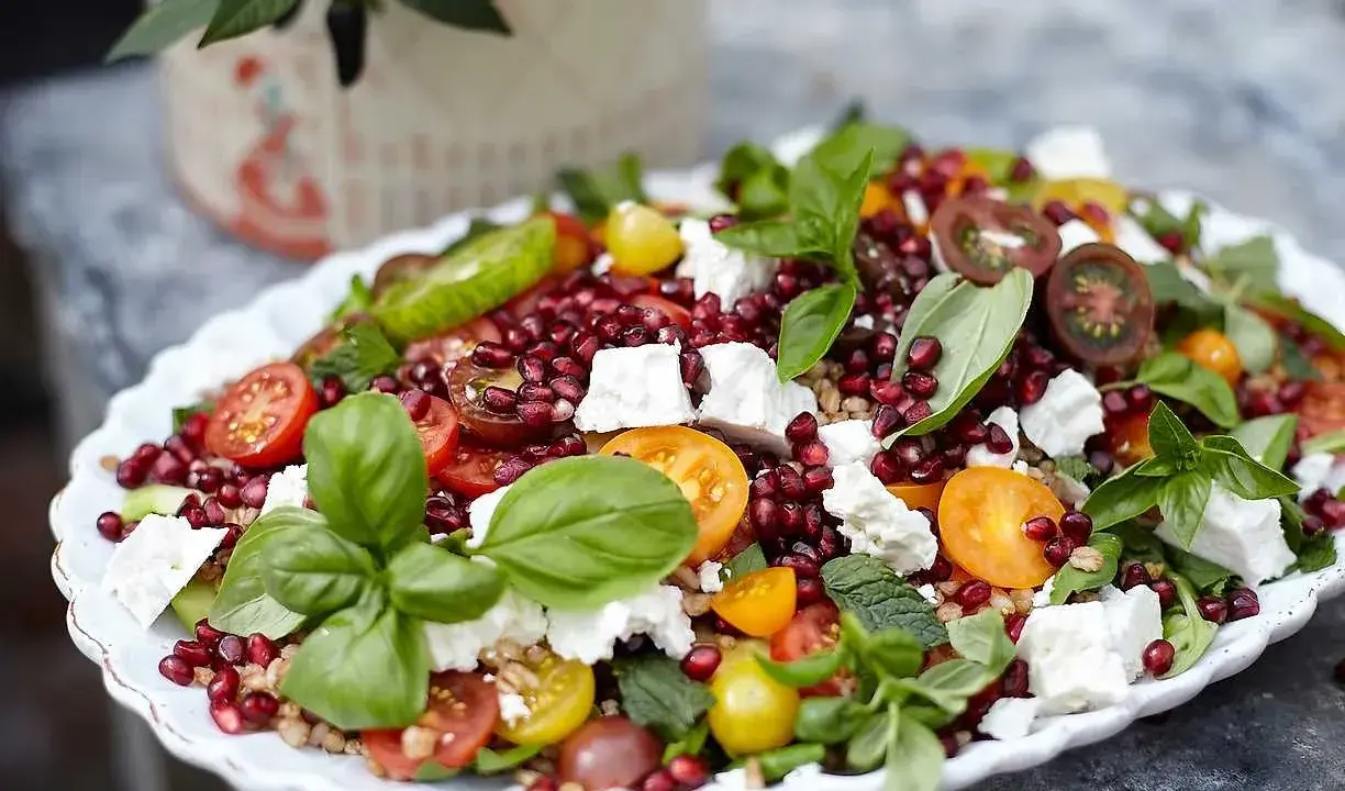 En färgsprakande sallad med granatäpple, tomat, fetaost och basilika. Ett perfekt kålmaja recept för sommaren.