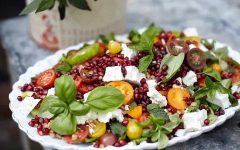En färgsprakande sallad med granatäpple, tomat, fetaost och basilika. Ett perfekt kålmaja recept för sommaren.