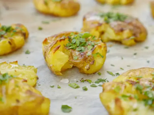 Krispiga smashed potatoes med ost och persilja, redo att serveras.