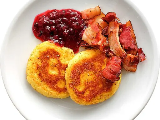 Två gyllene potatisbullar med lingonsylt och knaperstekt bacon. Ett klassiskt recept på potatisbullar som passar perfekt till frukost eller middag.