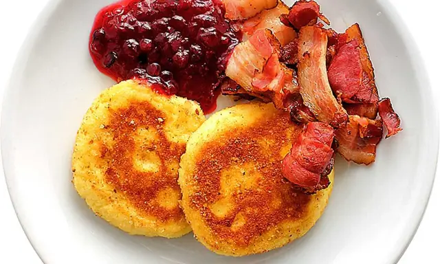 Två gyllene potatisbullar med lingonsylt och knaperstekt bacon. Ett klassiskt recept på potatisbullar som passar perfekt till frukost eller middag.