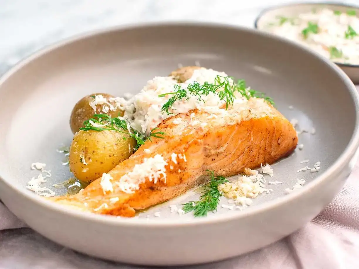 En saftig laxfil&eacute; med sm&aring;potatis och en kr&auml;mig roms&aring;s till laxen, garnerad med dill och riven ost.
