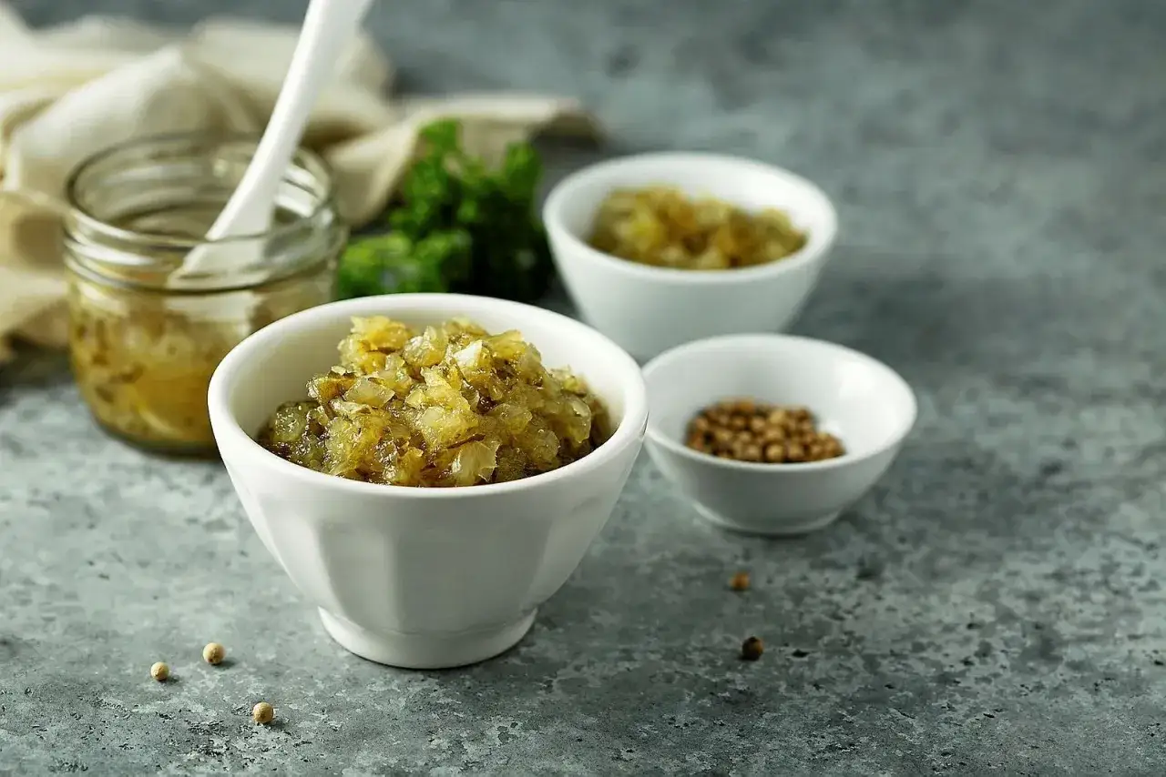 En sk&aring;l med finhackad bostongurka, perfekt f&ouml;r ditt bostongurka recept. Bredvid syns en burk med mer gurka och en sk&aring;l med senapsfr&ouml;n.