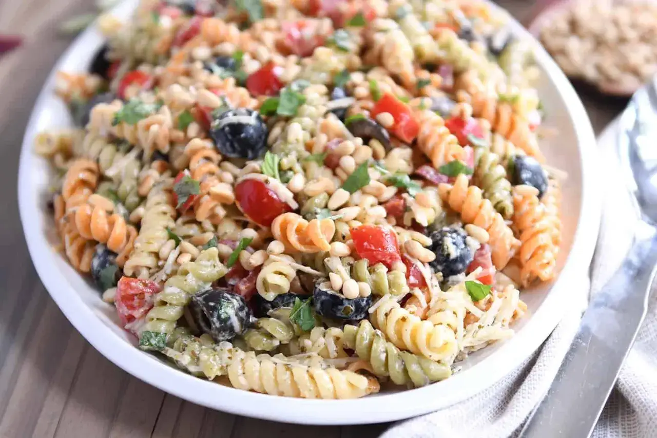En härlig pastasallad vegetarisk med fusilli, körsbärstomater, svarta oliver och pinjenötter. Perfekt för en lätt lunch!