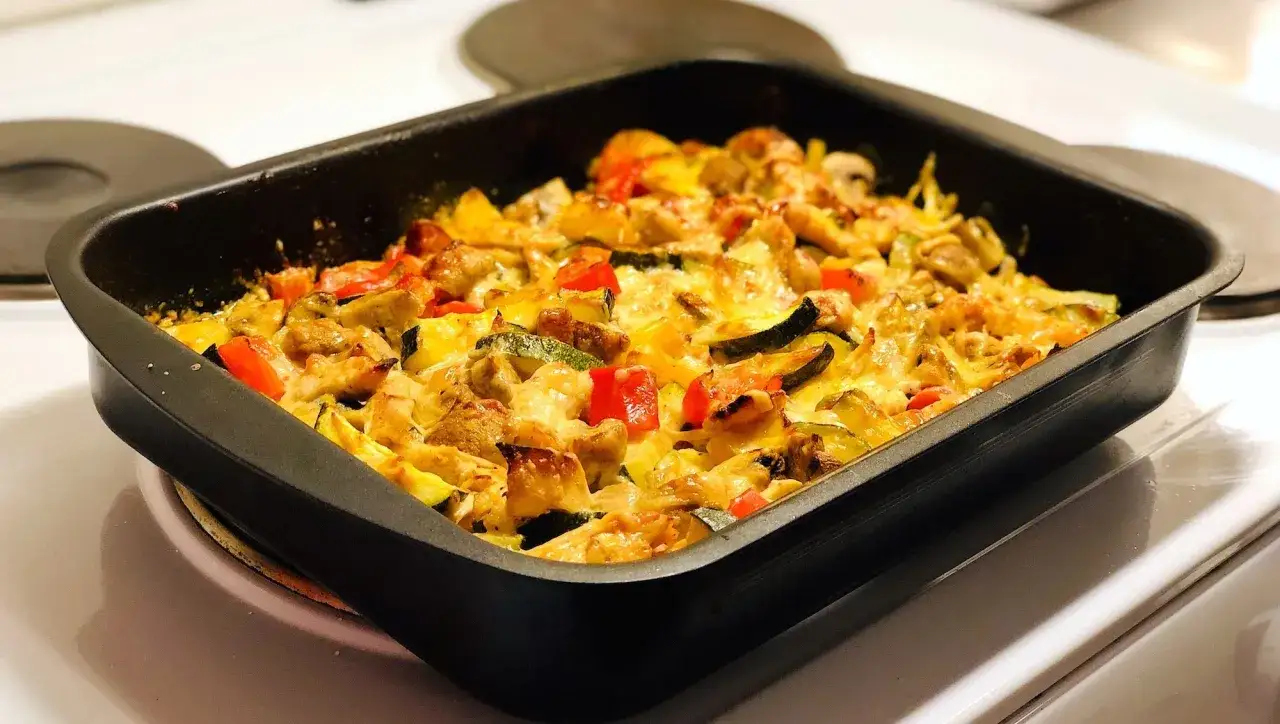 En ugnsform med strimlad kyckling, zucchini, paprika och svamp, täckt med smält ost. Ett perfekt strimlad kyckling recept för en snabb middag.