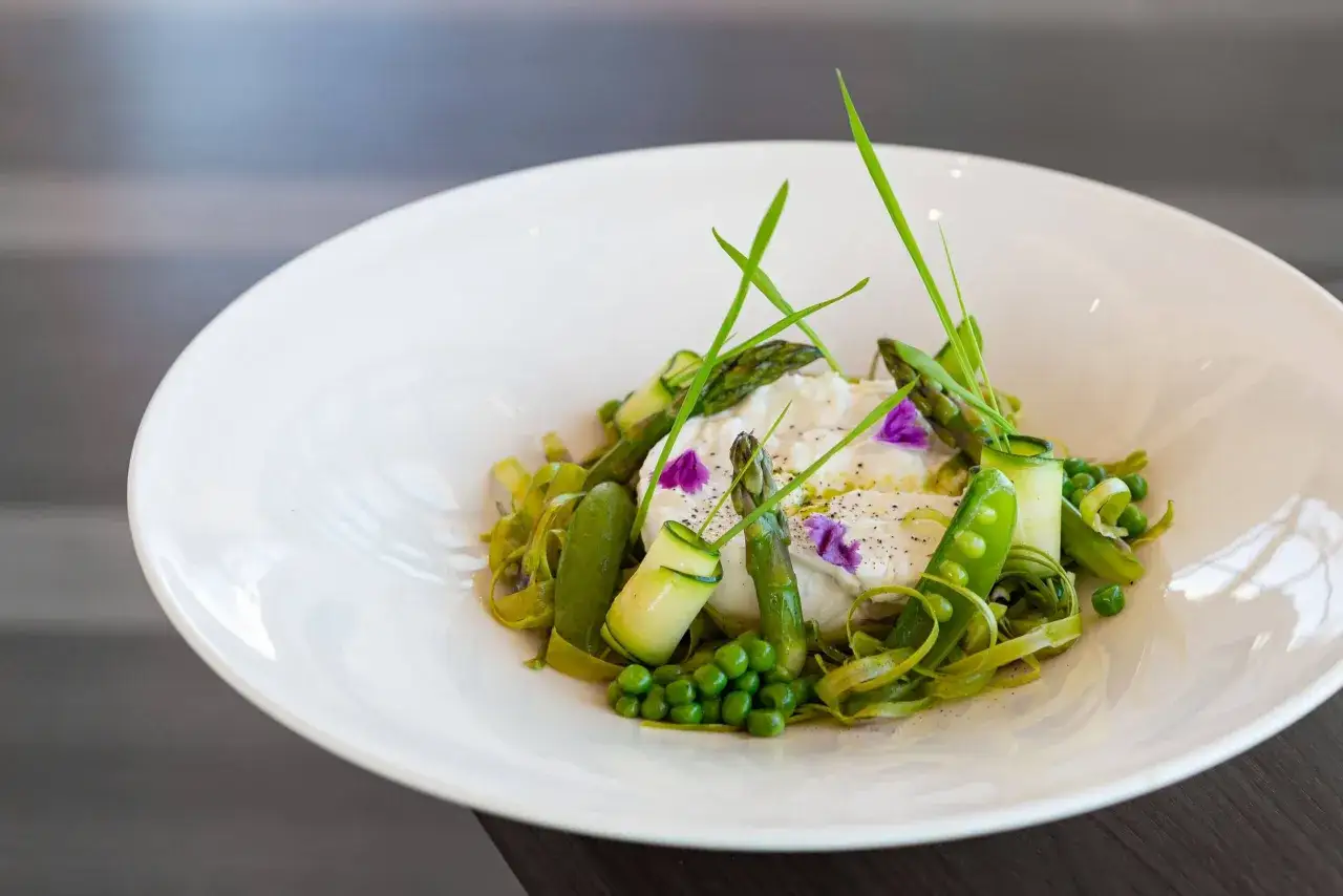 En lyxig sallad till buffé med krämig ost, sparris, sockerärtor och gurka, garnerad med örter och blommor.