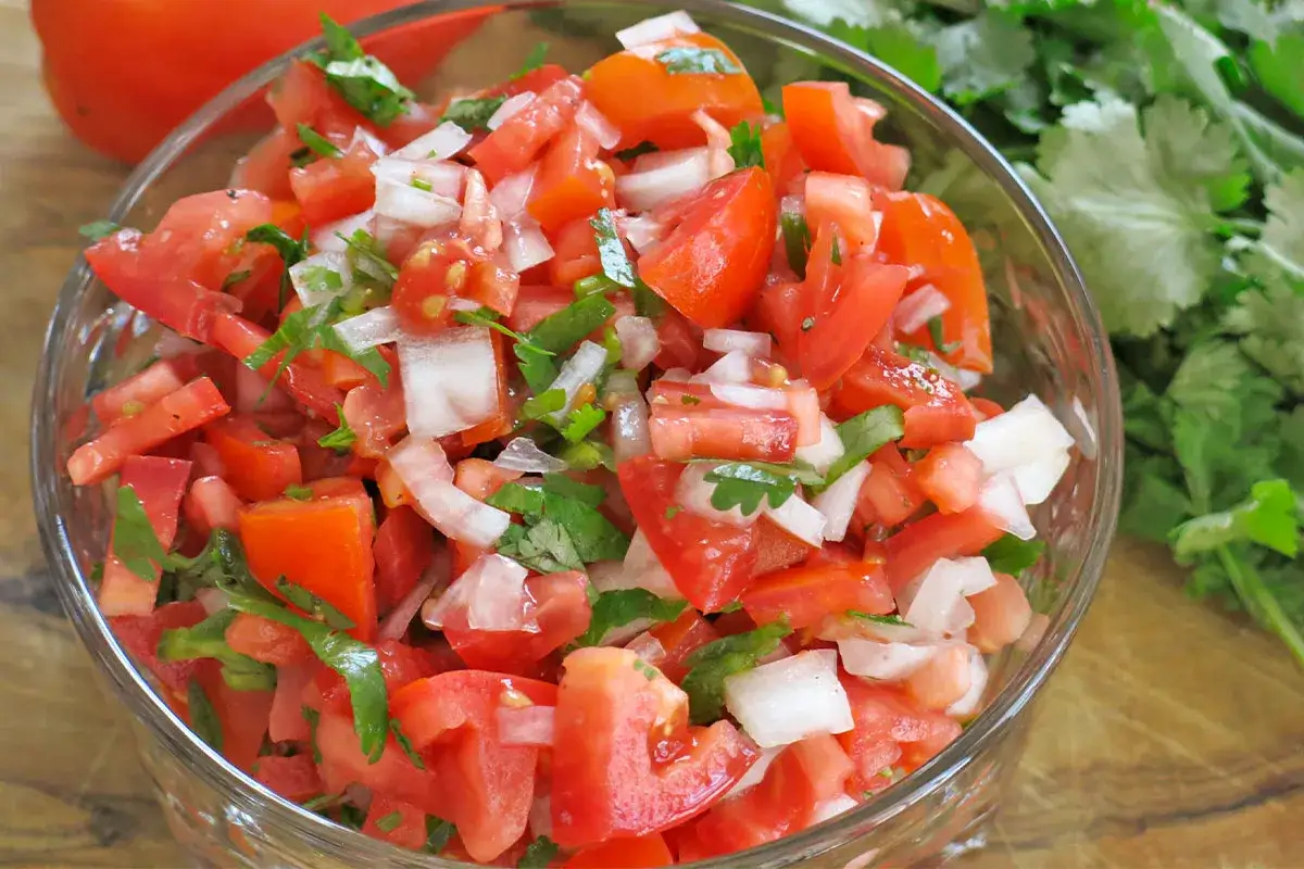 En skål med färsk pico de gallo, full av tärnade tomater, lök och koriander. Perfekt till tacosen!