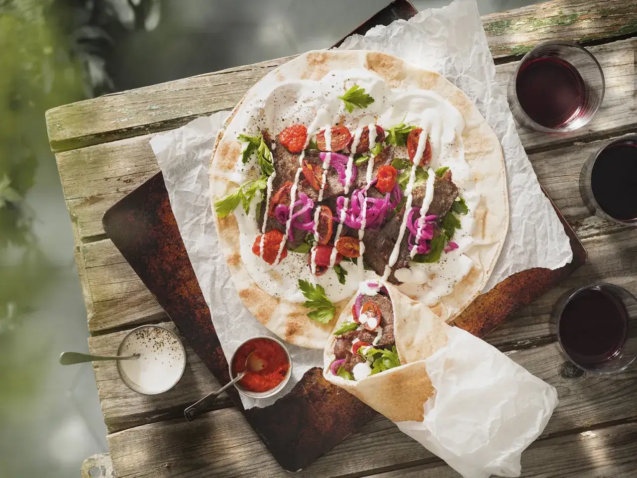 En l&auml;cker kyckling kebab p&aring; ett plattbr&ouml;d med tomater, l&ouml;k och vit s&aring;s. En annan kebabrulle ligger bredvid.