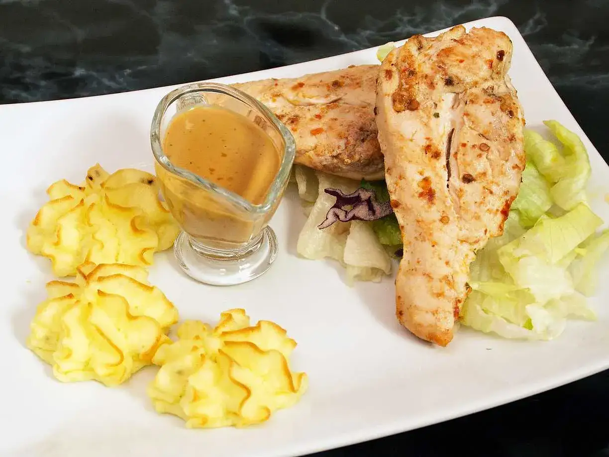 Två saftiga kycklingfiléer med en härlig marinad, serverade med potatisrosor, sallad och en krämig sås.